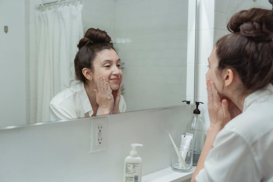 10 gestes maquillage pour retrouver un teint frais et lumineux woman applying skincare morning routine bathroom mirror natural light