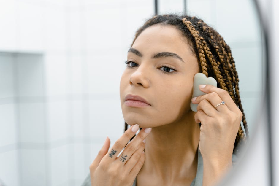 Massage facial revolumisant : le rituel de 10 minutes pour une peau repulpée woman performing facial massage with fingertips in natural light bathroom