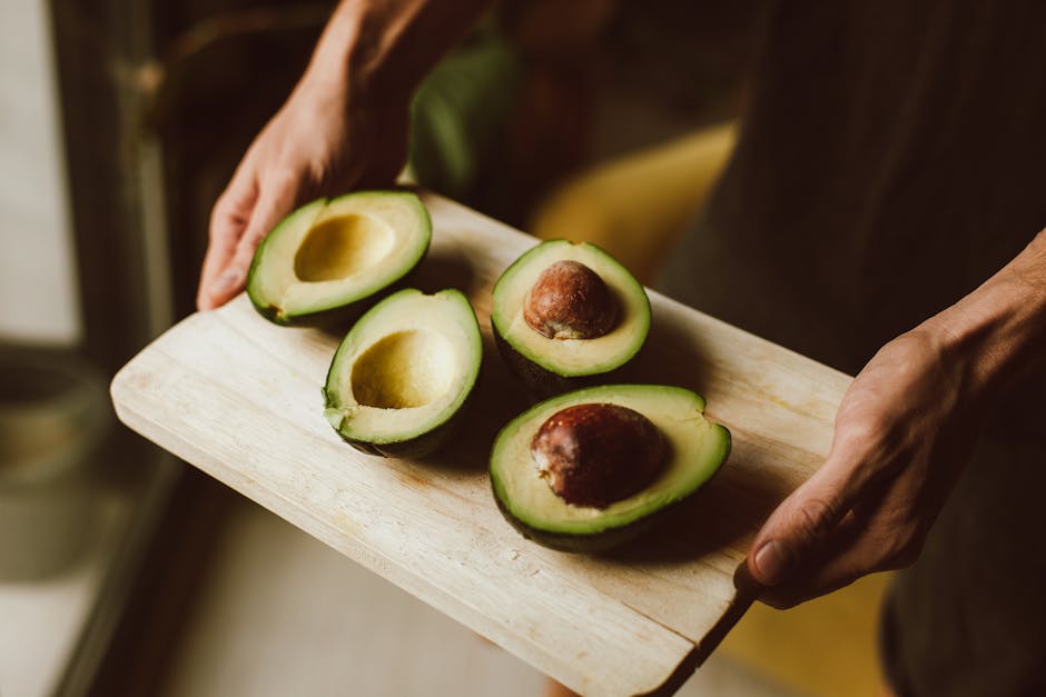 Avocat et peau : 10 raisons de l'inviter dans votre assiette chaque jour fresh avocado cut in half on wooden board with green leaves