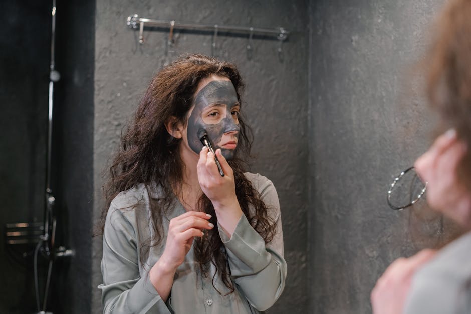3 gestes express pour retrouver un teint éclatant avant une soirée woman applying face scrub in bathroom mirror before evening event