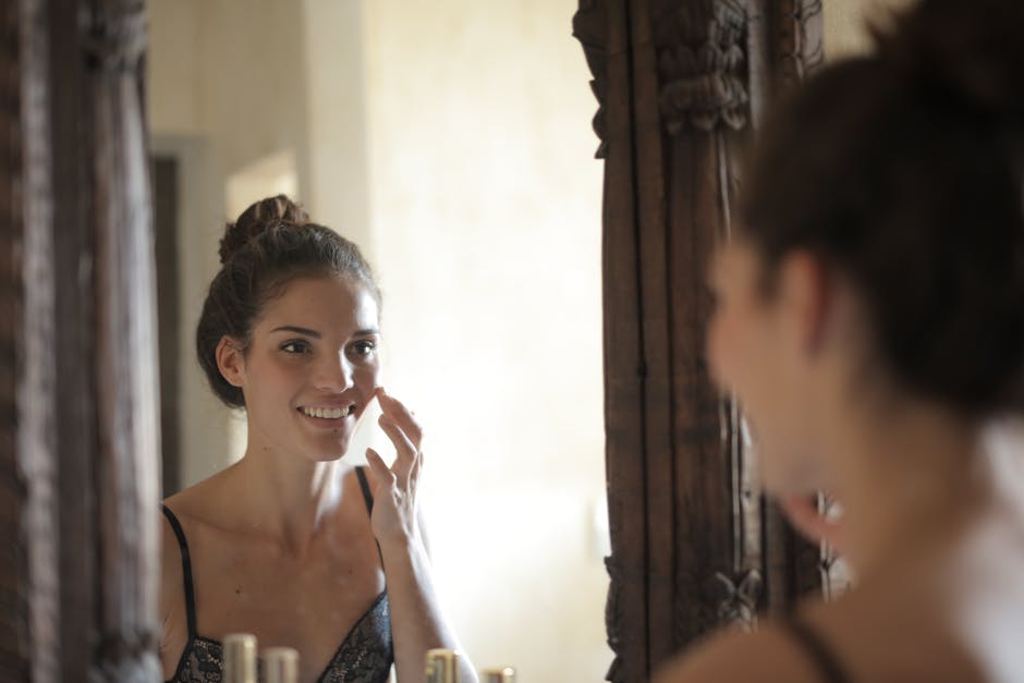 woman night skincare routine applying face cream bedroom mirror