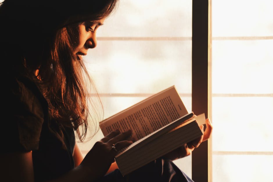 person sitting in natural sunlight reading book relaxed