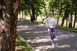 5 bonnes raisons de se mettre à la course à pied cette saison woman jogging in a sunny park surrounded by green trees landscape