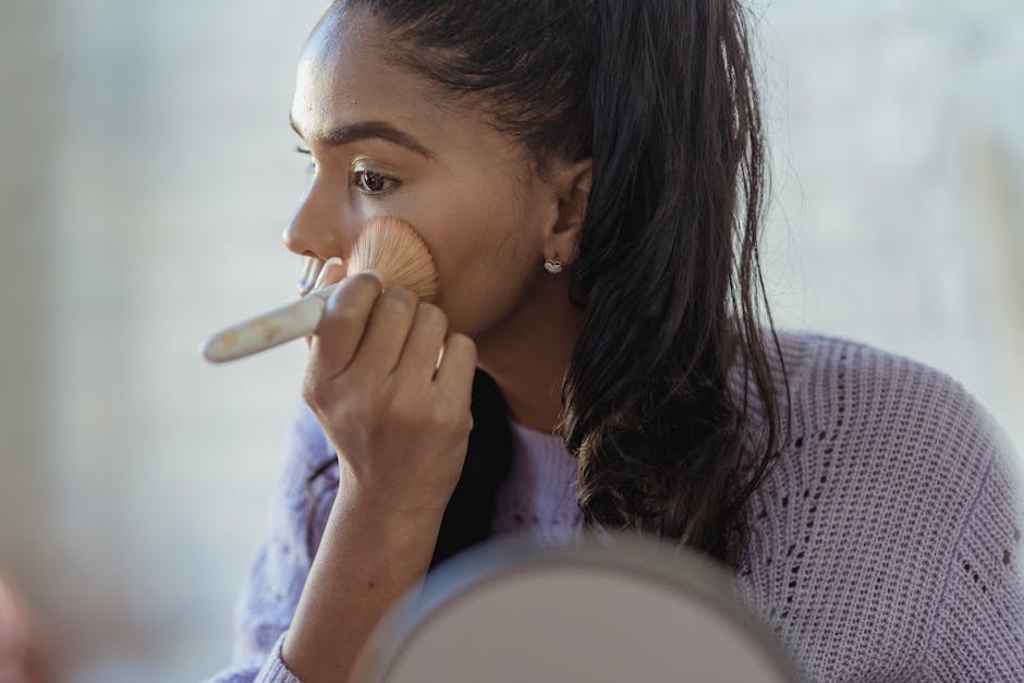 Paraître plus jeune : 8 astuces beauté et style pour gagner des années woman applying light foundation with brush natural makeup glow
