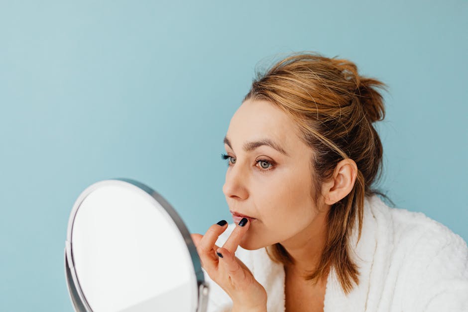 Rajeunir son sourire : soins, astuces make-up et solutions esthétiques woman applying lip care cream looking in mirror natural light