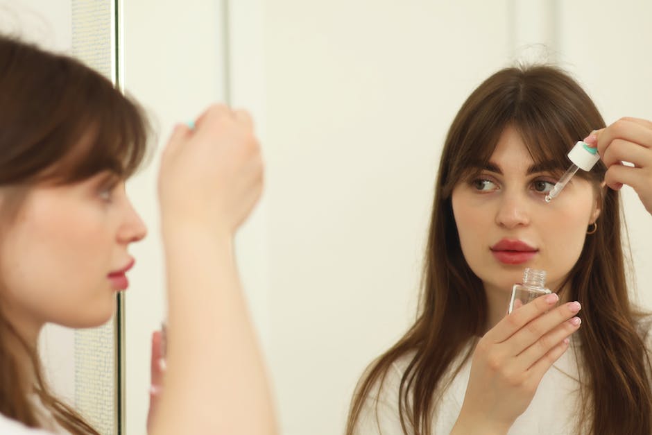 woman applying serum face mirror morning light
