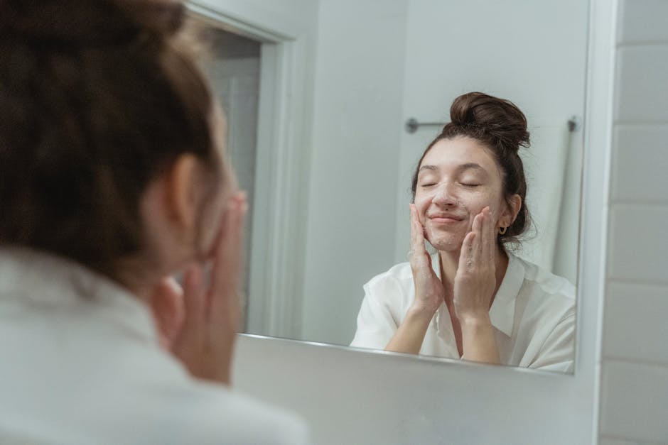 En finir avec les imperfections : routine nettoyage, soins et camouflage en 3 étapes woman cleansing face with foam cleanser bathroom mirror