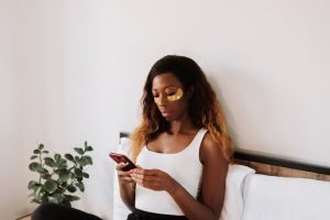 Smartphone et rides : comment le « text-neck » vieillit votre peau (et comment y remédier) woman smartphone skincare neck care routine natural light landscape