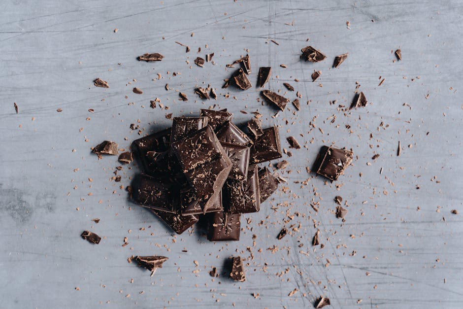 Alimentation et peau : les aliments clés pour un teint éclatant et une peau ferme dark chocolate pieces with cocoa powder on dark background