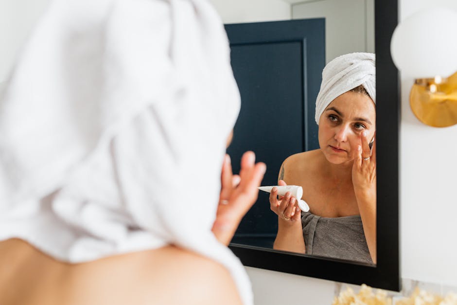 Hydrater ou nourrir sa peau : comment choisir le bon soin selon ses besoins ? woman applying moisturizer on face in front of mirror skincare routine