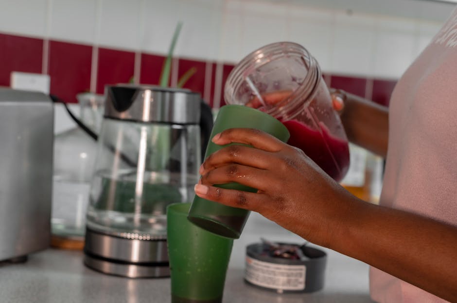 Spiruline : bienfaits anti-âge, détox et énergie pour la peau et l'organisme woman drinking green smoothie with spirulina healthy lifestyle kitchen