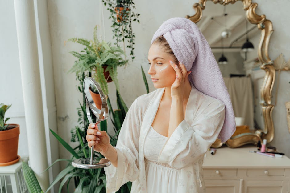 Soin contour des yeux : comment choisir la bonne formule pour un regard rajeuni woman using metal applicator eye cream morning routine bathroom mirror