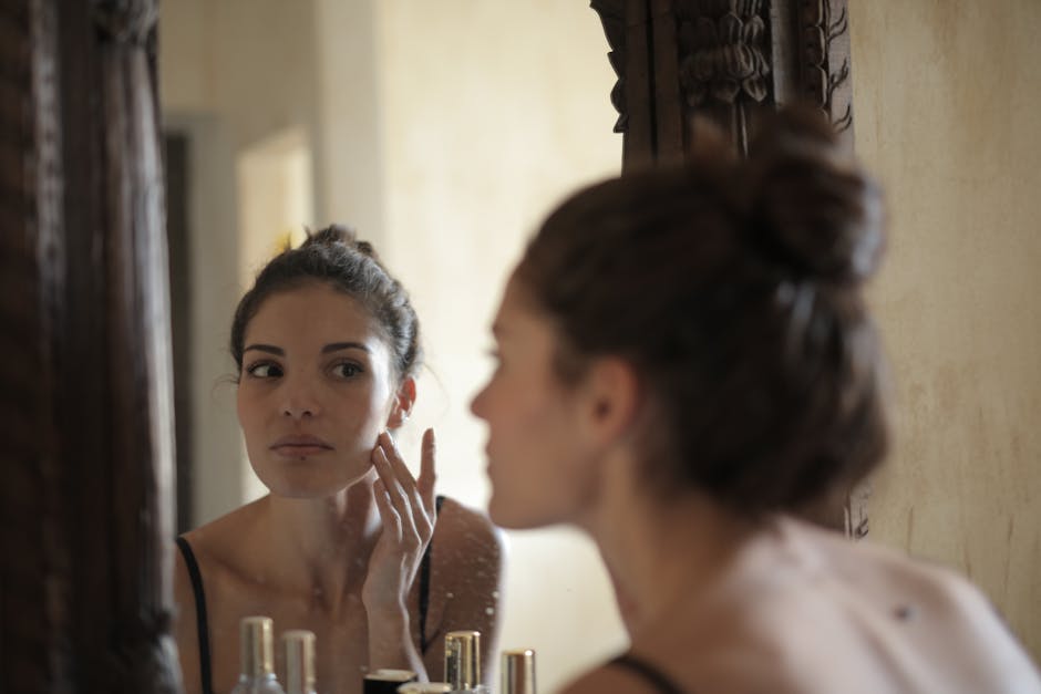 Sérum volumateur après 40 ans : comment retrouver des volumes et un visage redéfini mature woman touching cheeks looking in mirror natural light