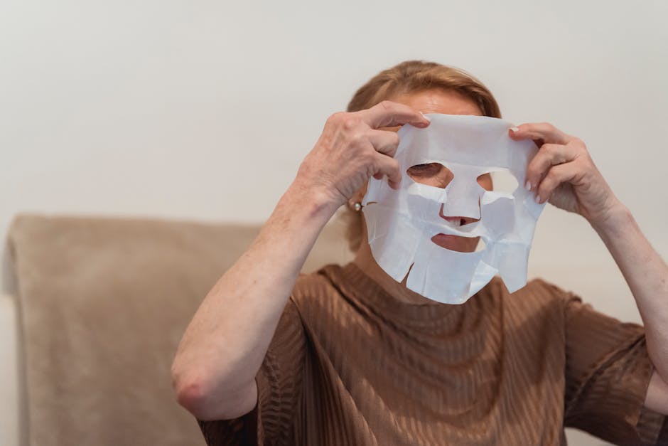 Glossaire beauté : 10 termes cosmétiques tendance décryptés woman applying sheet mask on face with soft lighting