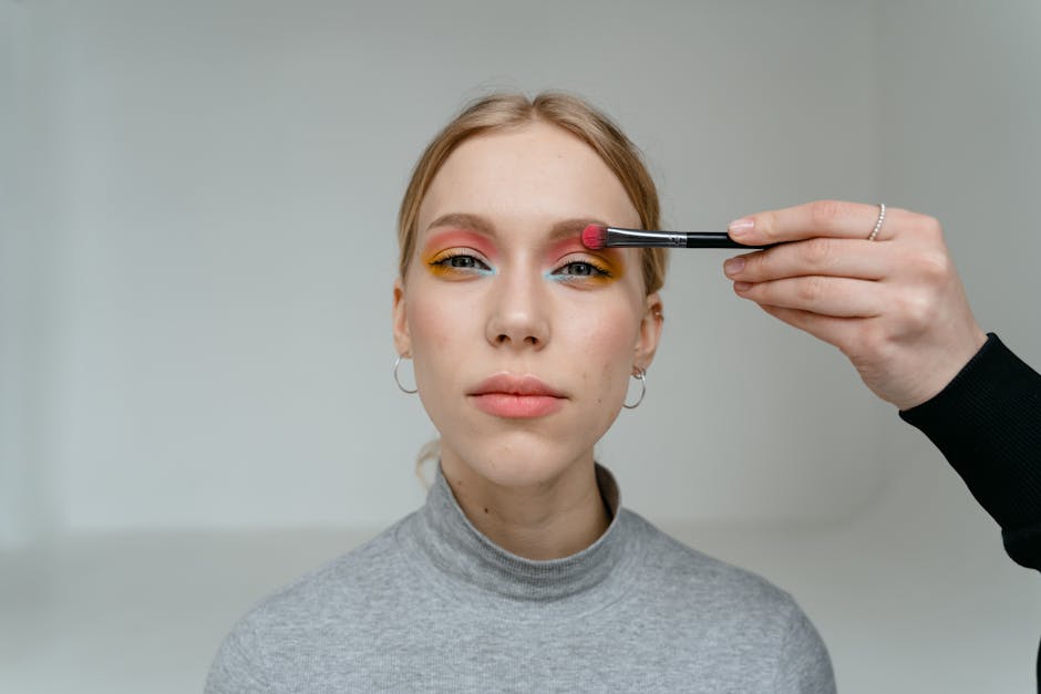Regard fatigué : 5 gestes simples pour retrouver des yeux lumineux et reposés woman applying concealer under eye area with brush natural makeup look