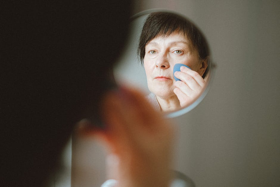 Peau à 65 ans : comprendre les changements et adapter sa routine beauté mature woman applying face cream mirror natural light