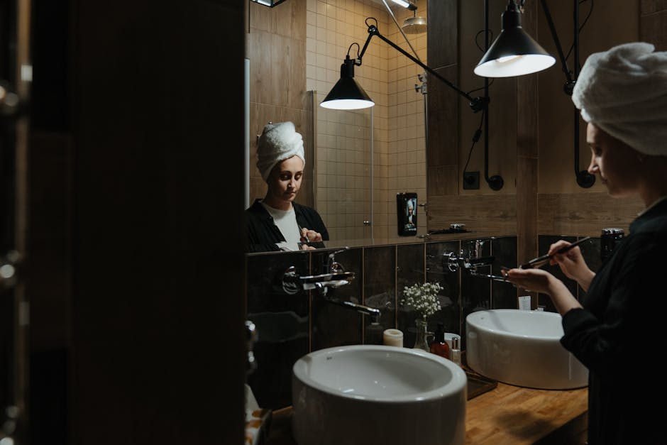 Alternatives au démaquillage classique : 4 méthodes douces pour une peau nette woman cleansing face gently with soft brush in bathroom mirror