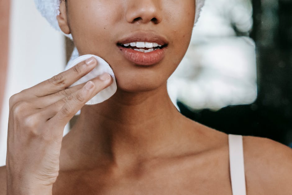 woman applying toner with cotton pad at night skincare routine