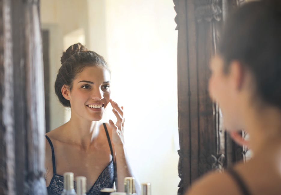 Hormones et peau : comment elles influencent votre épiderme à chaque étape de la vie young woman looking at her skin in the mirror natural light beauty