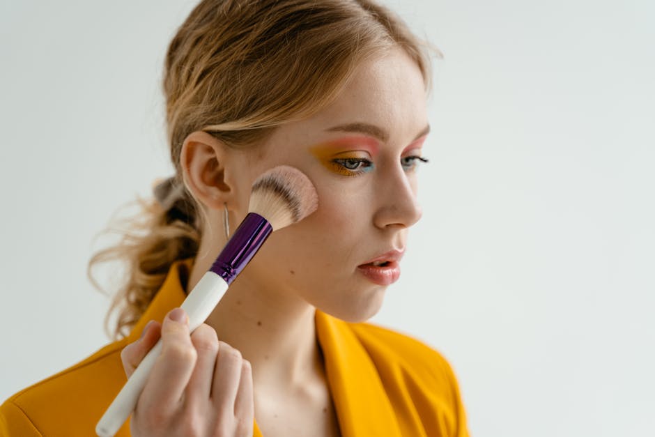 Maquillage anti-âge : les techniques essentielles pour un visage rajeuni woman applying blush on cheekbones with brush soft natural light