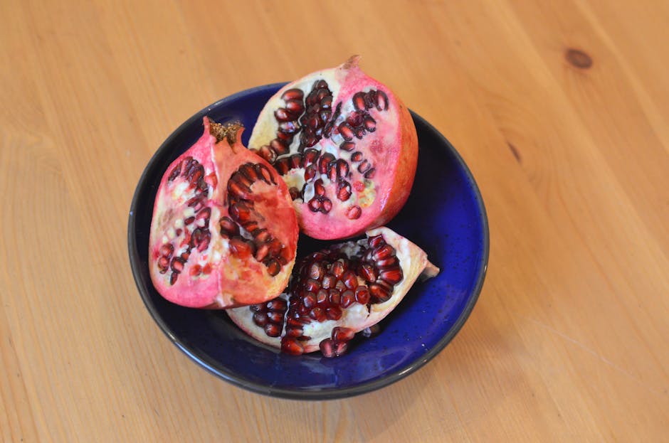 Grenade et peau : les bienfaits anti-âge de ce superfruit pour votre épiderme pomegranate fruit cut open showing red seeds on wooden table