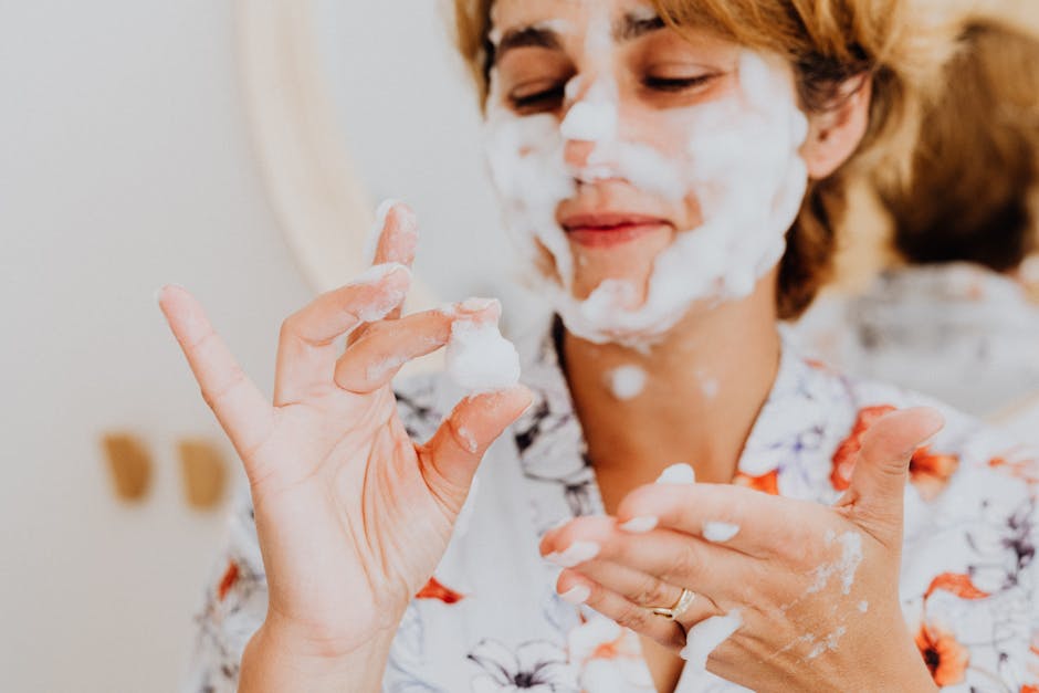 Teint nude réussi : les gestes essentiels pour une peau lumineuse sans effet masque woman cleansing face gently with foam cleanser natural light bathroom