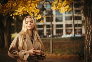 Protection solaire en automne : pourquoi continuer à se protéger après l'été woman autumn outdoor skincare sunscreen protection golden leaves landscape