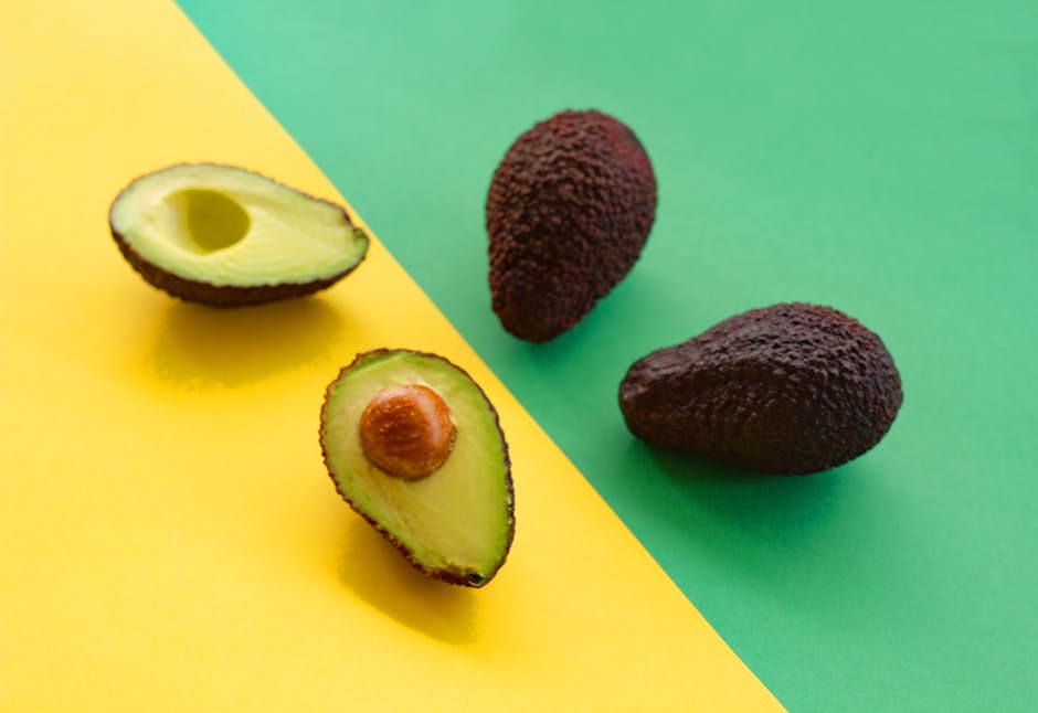 sliced avocado small bottle dark green avocado oil neutral background