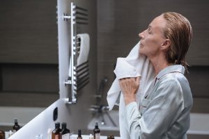 Rides du sommeil : causes, prévention et solutions pour atténuer ces marques nocturnes woman morning skincare routine mirror soft light bathroom landscape