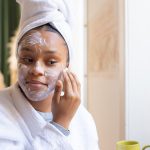 woman with glowing matte skin applying skincare products morning light