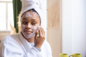 woman with glowing matte skin applying skincare products morning light