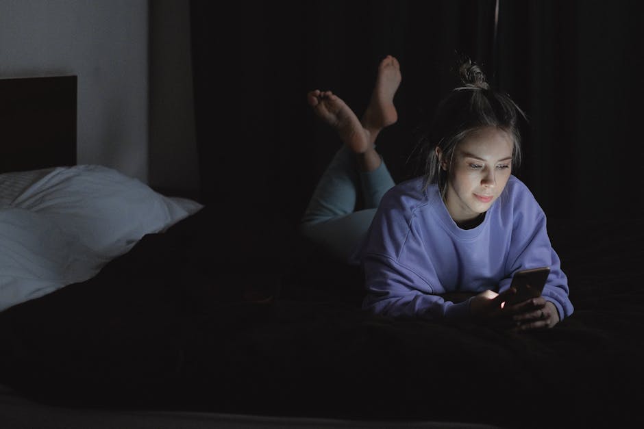 10 agressions extérieures qui fragilisent votre peau au quotidien person scrolling phone dark room blue light screen exposure