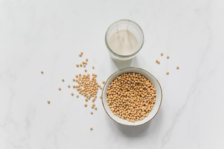 Huile de soja en cosmétique : bienfaits, actifs et conseils d'utilisation soybean oil glass bottle soybeans wooden table natural light