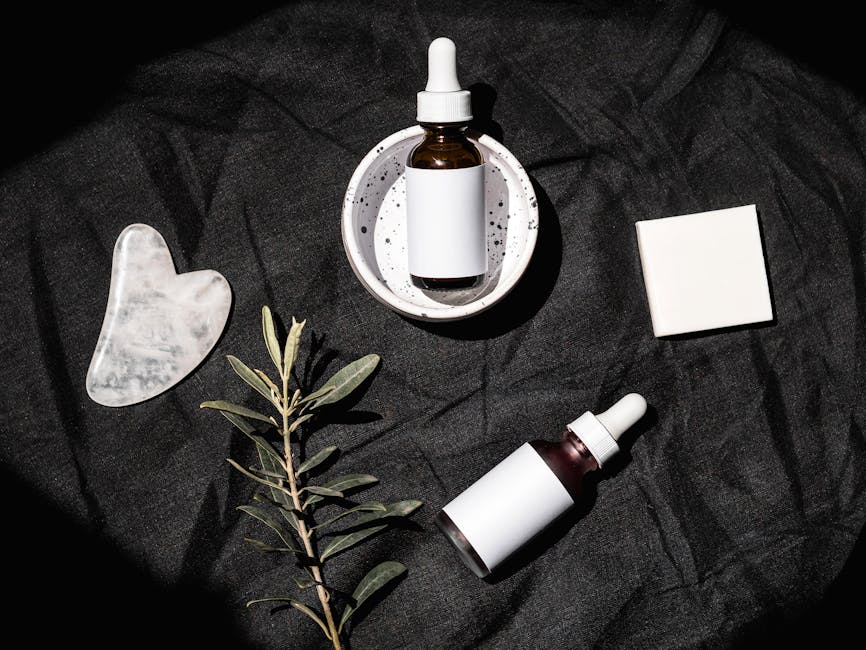 organic skincare products flat lay with green leaves and glass bottles